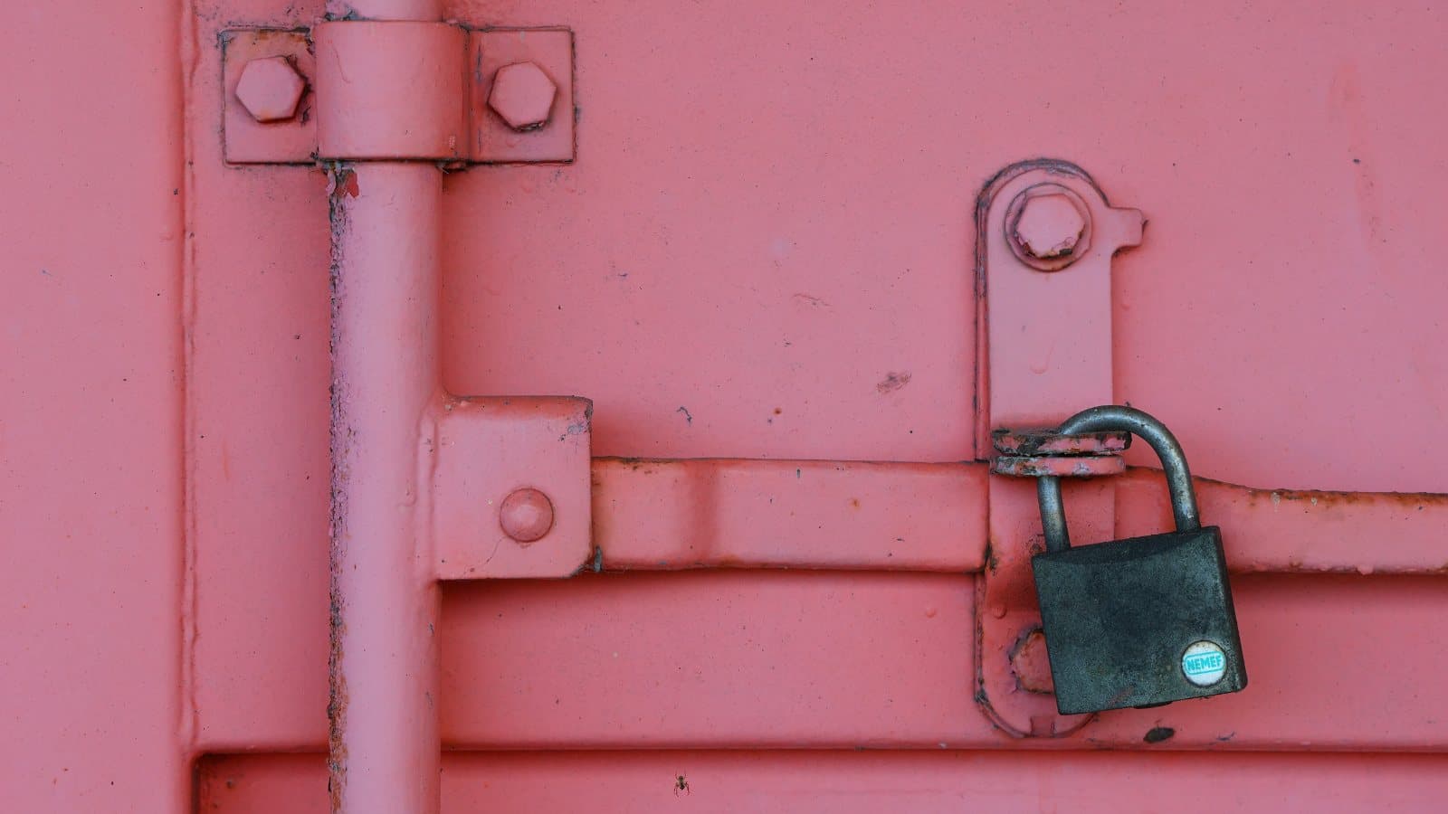 A padlock on the locking bar of a shipping container door