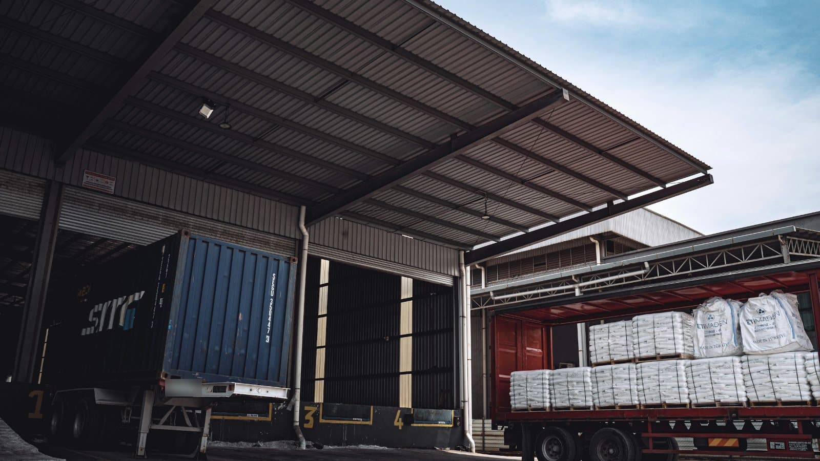 A trailer loaded with pallets of bagged goods at a warehouse loading dock